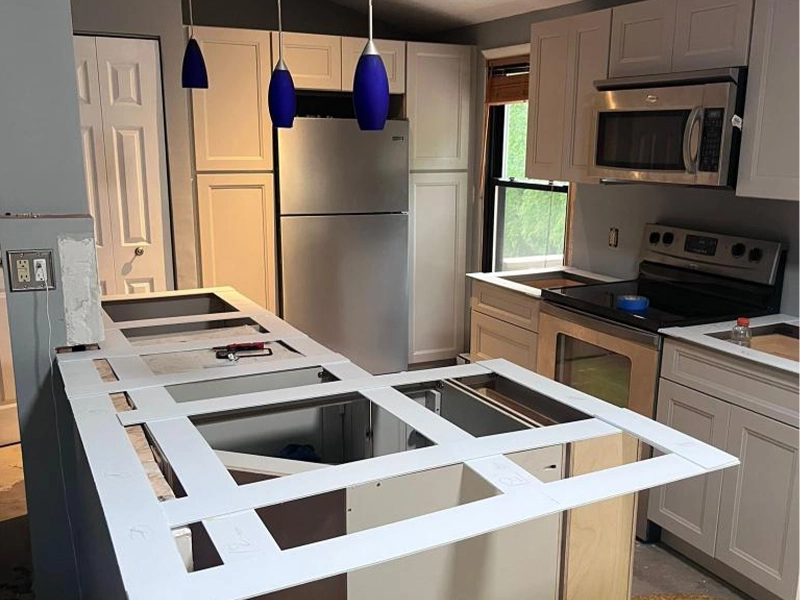Kitchen under renovation with new cabinets, stainless steel appliances, and an unfinished countertop frame.