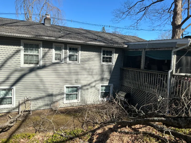Gray house exterior with multiple windows and a screened porch on a sunny day.